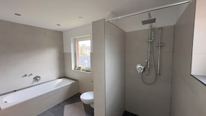 Ein modernes Badezimmer mit Badewanne, Toilette und Dusche.