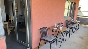An outdoor seating area with tables and chairs, a glass door entrance, and a pink wall. - MainNest Marktbreit - Family Apartment (Marktbreit)