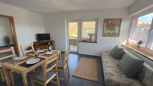 A dining area with a wooden table set for two, a sofa, and a TV on a stand. - MainNest Marktbreit - Family Apartment (Marktbreit)