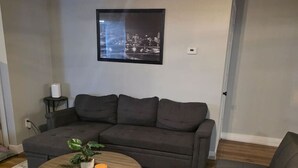 A living room with a grey sofa, a round coffee table, and a patterned rug. - Quiet 2 Bedroom Escape Steps from Downtown Joliet (Joliet)