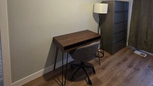 A room with a wooden desk, a chair, a floor lamp, and a dark-colored cabinet. - Quiet 2 Bedroom Escape Steps from Downtown Joliet (Joliet)