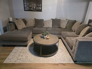A living room with a sectional sofa, a round coffee table, and a patterned rug. - Quiet 2 Bedroom Escape Steps from Downtown Joliet (Joliet)