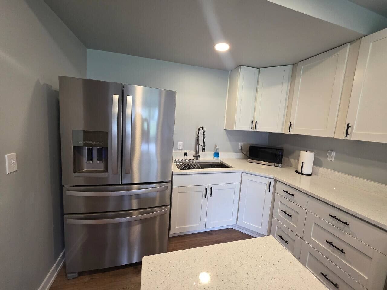 A modern kitchen with stainless steel appliances, white cabinetry, and a granite countertop.