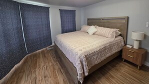 A bedroom with a bed, a nightstand, a lamp, and a ceiling light fixture. - Quiet 2 Bedroom Escape Steps from Downtown Joliet (Joliet)