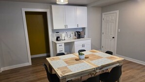 A dining area with a wooden table, black chairs, a small plant centerpiece, and white cabinets in the background. - Quiet 2 Bedroom Escape Steps from Downtown Joliet (Joliet)