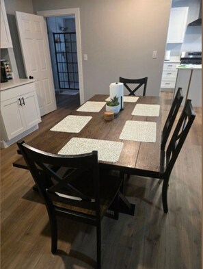 A dining area with a wooden table, four chairs, and a potted plant. - Quiet 2 Bedroom Escape Steps from Downtown Joliet (Joliet)