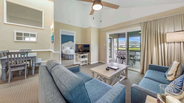 Ein Hotelzimmer mit Balkon, Deckenventilator, Fernseher, Essbereich und Sofa.