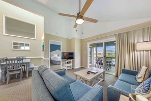 Ein Hotelzimmer mit Balkon, Deckenventilator, Fernseher, Essbereich und Sofa.
