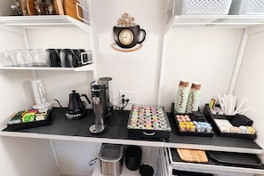 A coffee station with a coffee machine, cups, and a variety of coffee pods.