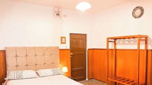 A hotel room with a bed, a wooden wardrobe, a bedside table with a lamp, and a wall clock. - Casona de San Agustin (Cusco)