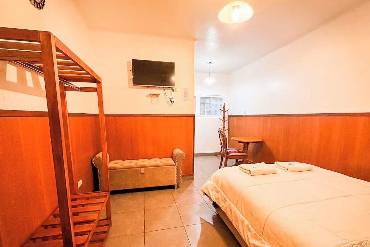 A room with a bunk bed, a sofa, a television, and a small table.
