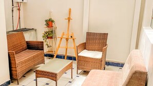 A room with wicker furniture, a small table, a chair, and an easel. - Casona de San Agustin (Cusco)