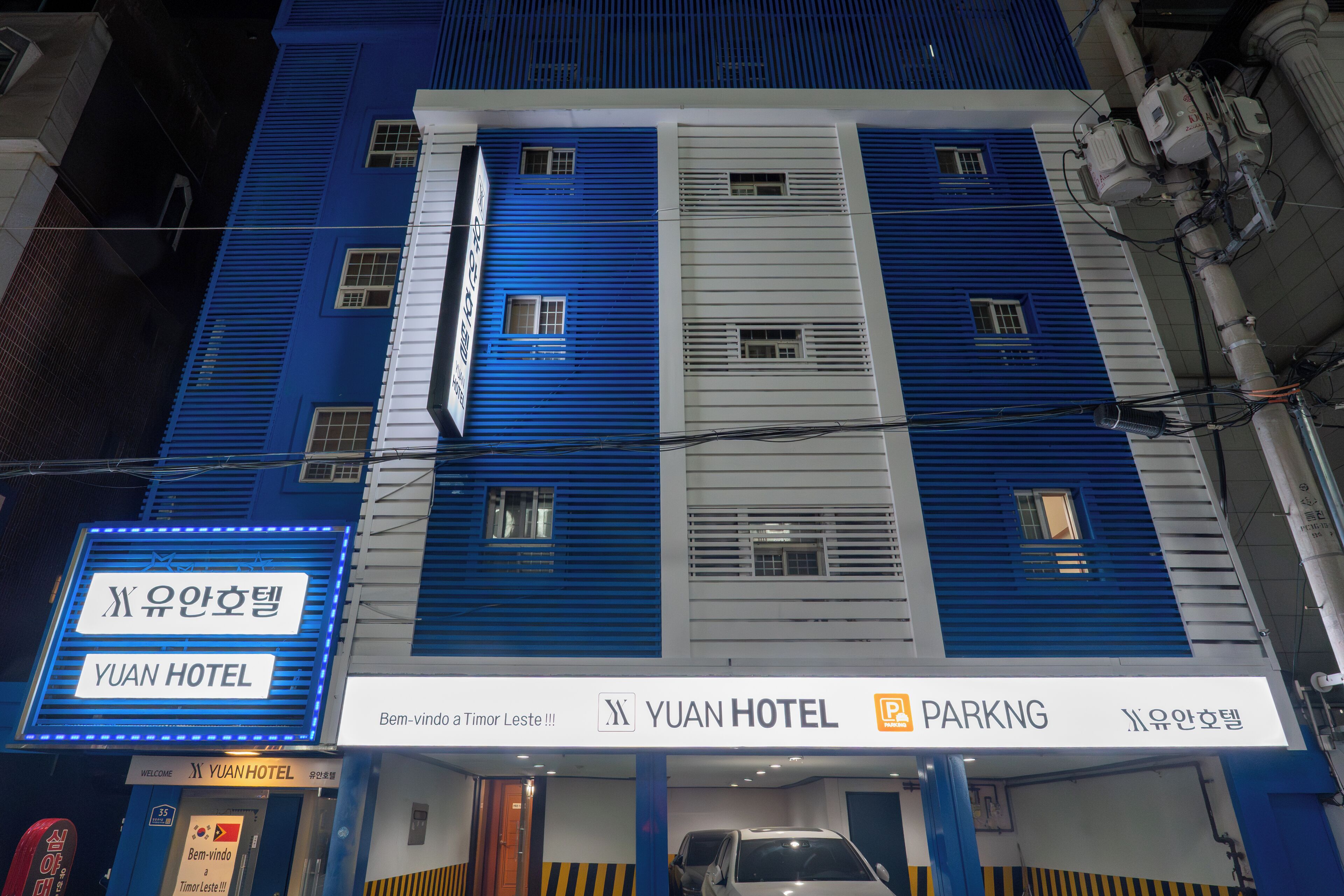 Edificio de hotel con señalización que indica 'YUAN HOTEL' y 'ESTACIONAMIENTO'.