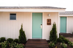 Um edifício térreo com porta verde, uma janela pequena e uma caixa de correio.