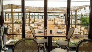 A restaurant with outdoor seating overlooking a body of water, featuring wicker chairs and tables. - Barlume Beach Montauk (Montauk)