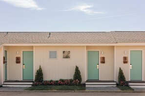 A row of three-story buildings with numbered doors, small windows, and a tiled roof. - Barlume Beach Montauk (Montauk)