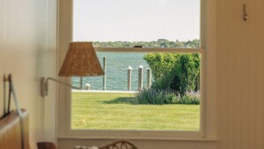 A bedroom with a large window, a bed, a lamp, and a view of a body of water. - Barlume Beach Montauk (Montauk)