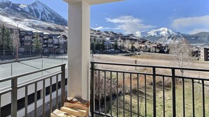 Un balcon offrant une vue sur une ville de montagne et sur des sommets enneigés.