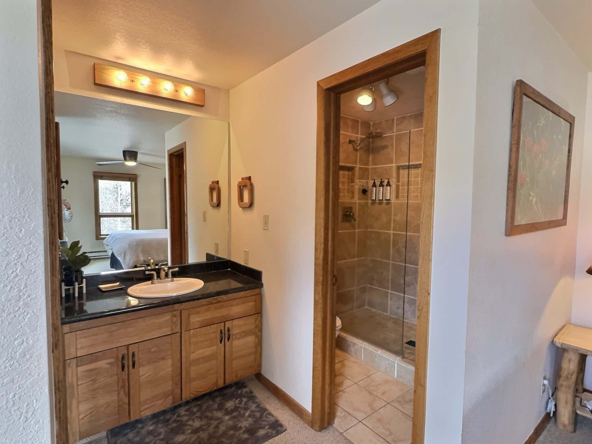 Une salle de bain avec un meuble-lavabo, un miroir et une douche.