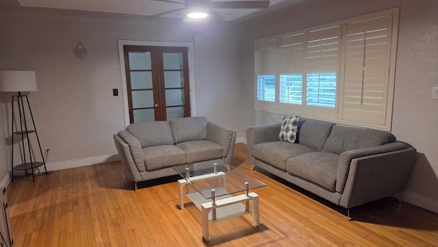 A living room with two grey sofas, a glass coffee table, a floor lamp, and a window with blinds. - Little oasis  2-bedroom house in fantastic St. Petersburg with AC (St. Petersburg)
