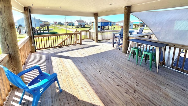 Une terrasse en bois offrant une vue sur un quartier résidentiel, une chaise bleue et une petite table.