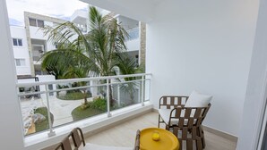 A balcony with a view of a residential area, a small table with a yellow object, and two chairs with cushions. - Modern Studio Pool Coral Azul Estrella Dominicus (Dominicus)