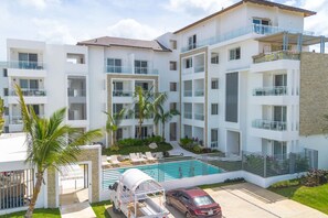 A multi-story hotel with balconies, a swimming pool, and a parking area.