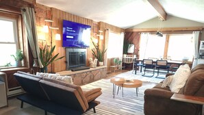 A cozy living room with a fireplace, sofas, and a television displaying a welcome message.