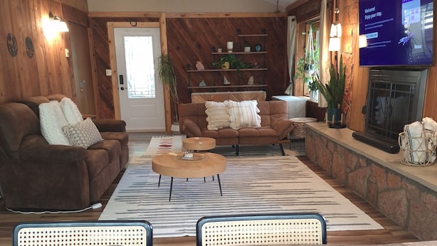 A cozy living room with a fireplace, a television, and a wooden wall.