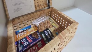 Una cesta de madera con un menú y aperitivos adentro.