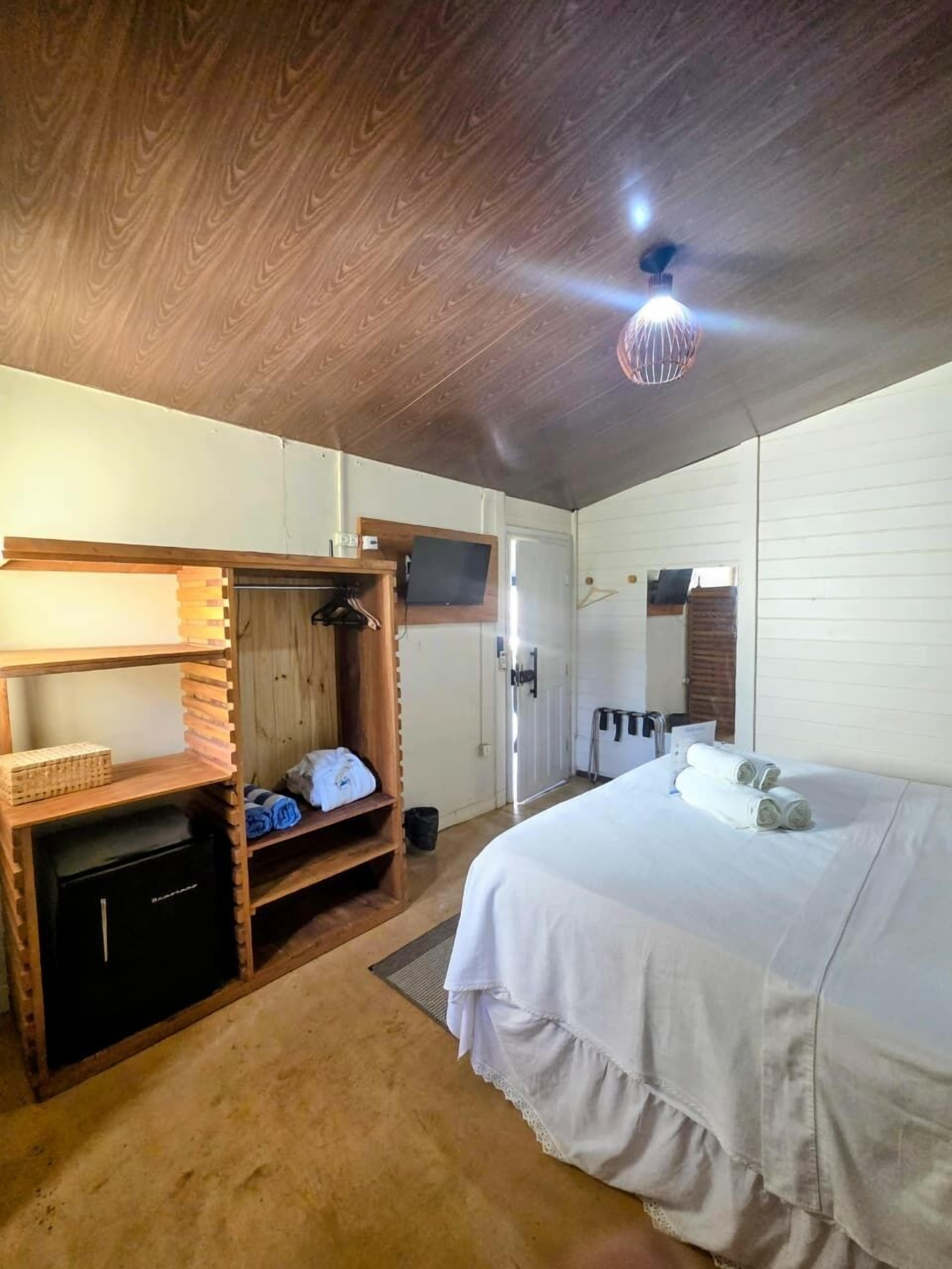 Une chambre à coucher avec un lit, une armoire en bois et un téléviseur.