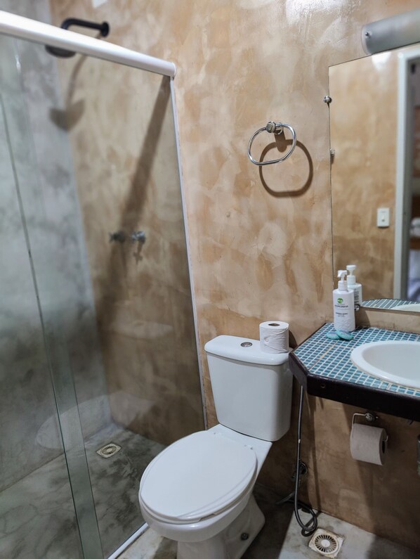 A bathroom with a toilet, a shower, and a sink with a mirror. - Liberty Noronha Sueste (Fernando de Noronha)