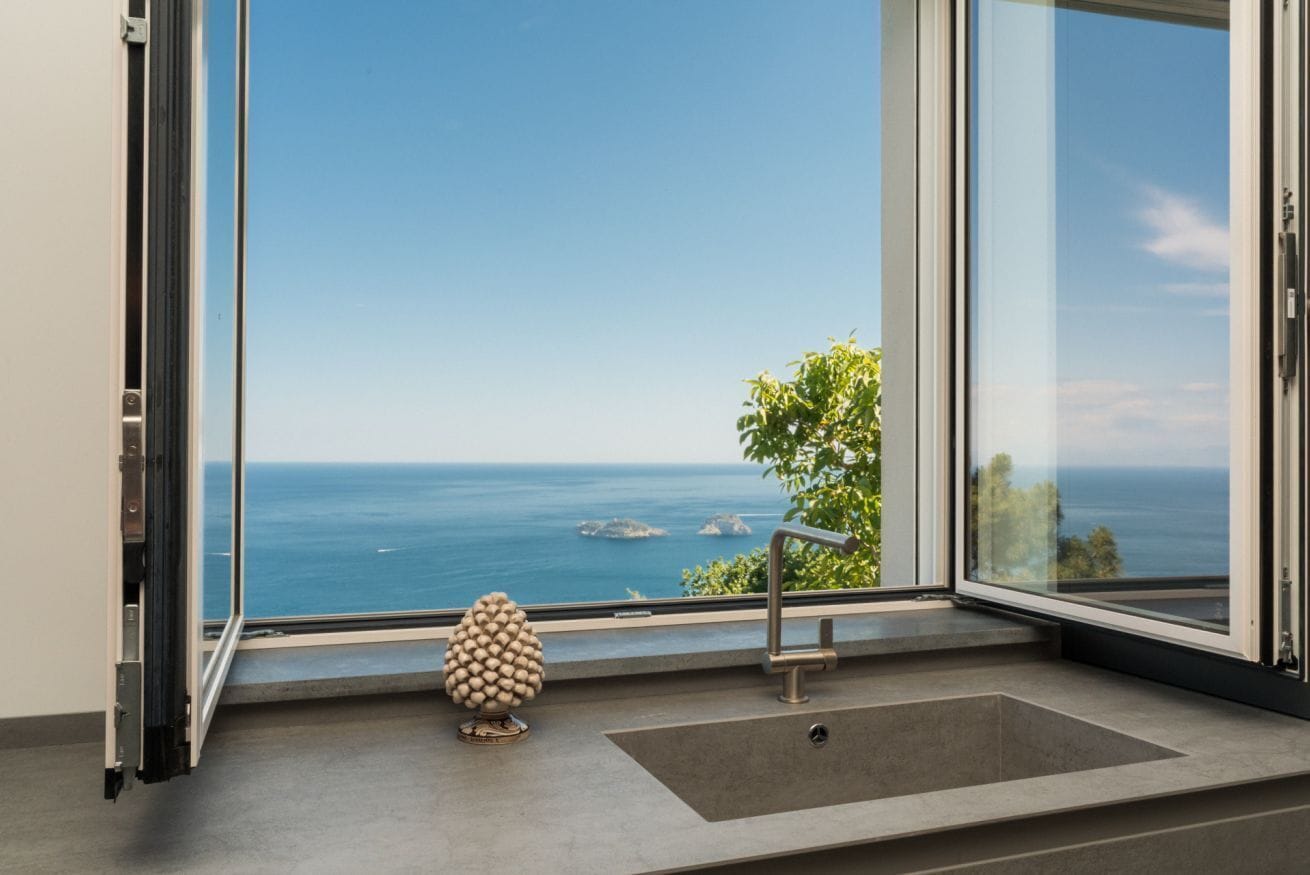 Un baño moderno con un ventanal grande, un lavabo y una piña decorativa.