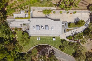 Une vue aérienne d’un bâtiment doté d’un toit plat, entouré de verdure et d’une allée incurvée.