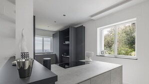 Una cucina moderna con un piano di lavoro scuro, un piano cottura integrato e una finestra che si affaccia sul verde.