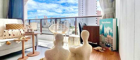 A modern living room with a city view, a sofa, a small table, and decorative items.
