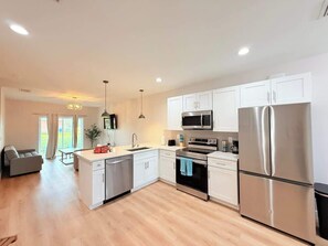 A modern kitchen with white cabinets, stainless steel appliances, and a wooden floor. - Stylish Comfort in Englewood 3BR 2BA, Great Location (Englewood)