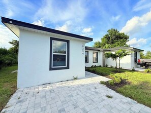 Ein modernes, eingeschossiges Haus mit befestigter Auffahrt und einem kleinen Garten.