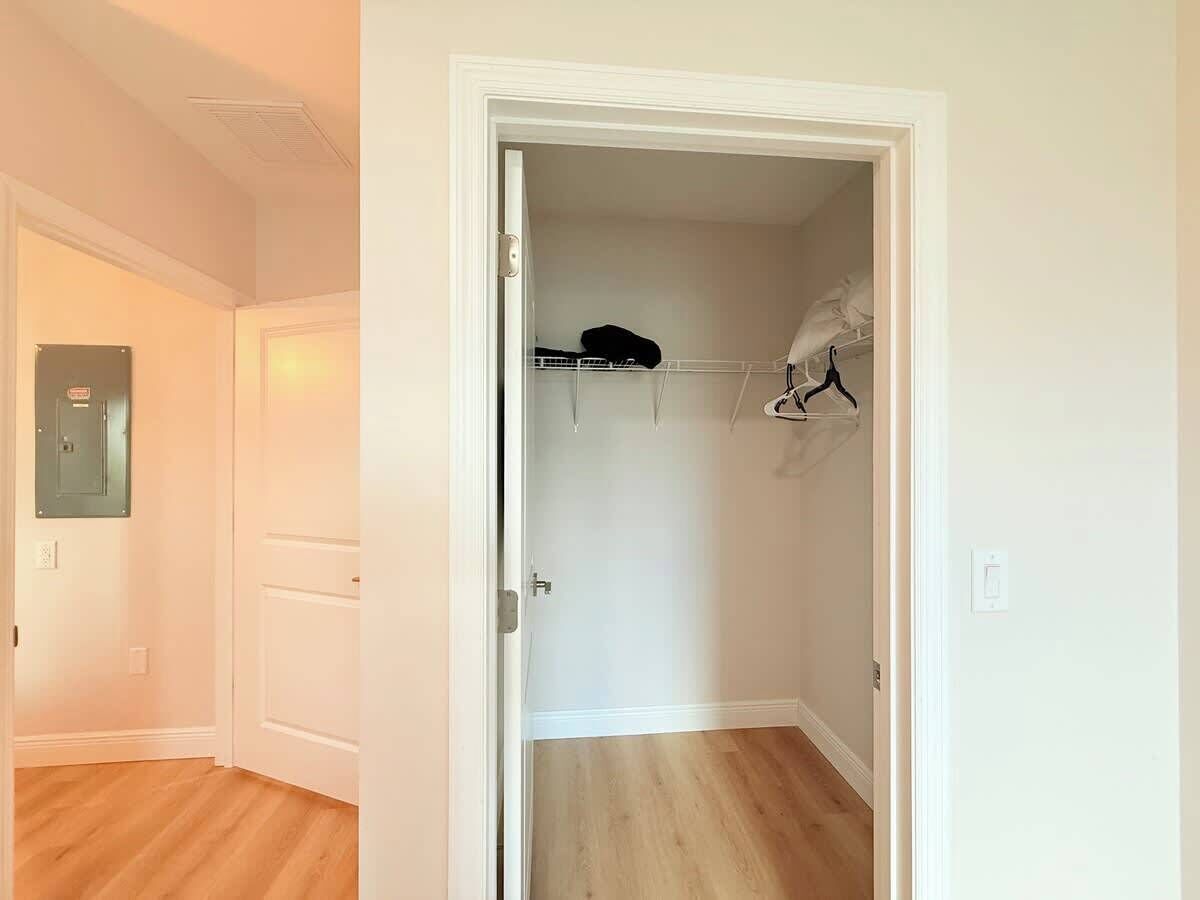 Ein Zimmer mit Holzboden, einer weißen Tür und einem Schrank mit Kleiderstange und Regalen.