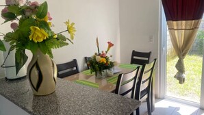 A dining area with a glass table, chairs, and a vase with flowers. - Spacious 7-bedroom house in beautiful San Miguel with AC (San Miguel)