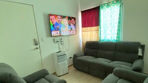 A living room with two grey sofas, a flat-screen TV mounted on the wall, and a window with curtains. - Spacious 7-bedroom house in beautiful San Miguel with AC (San Miguel)