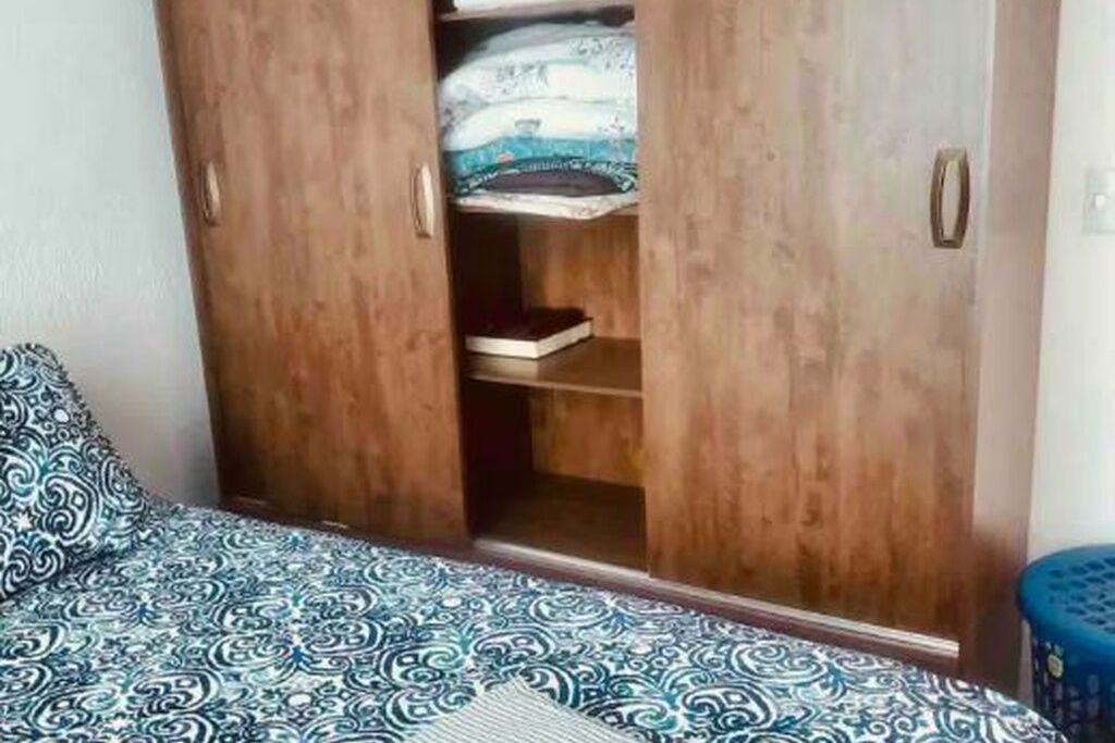 Une chambre à coucher avec un lit, une armoire et un tabouret bleu.