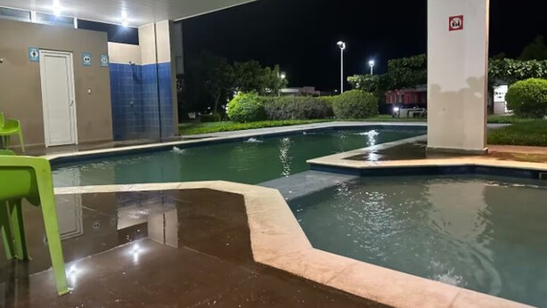 A swimming pool with a tiled edge, a green chair, and a door with a blue sign. - Spacious 7-bedroom house in beautiful San Miguel with AC (San Miguel)