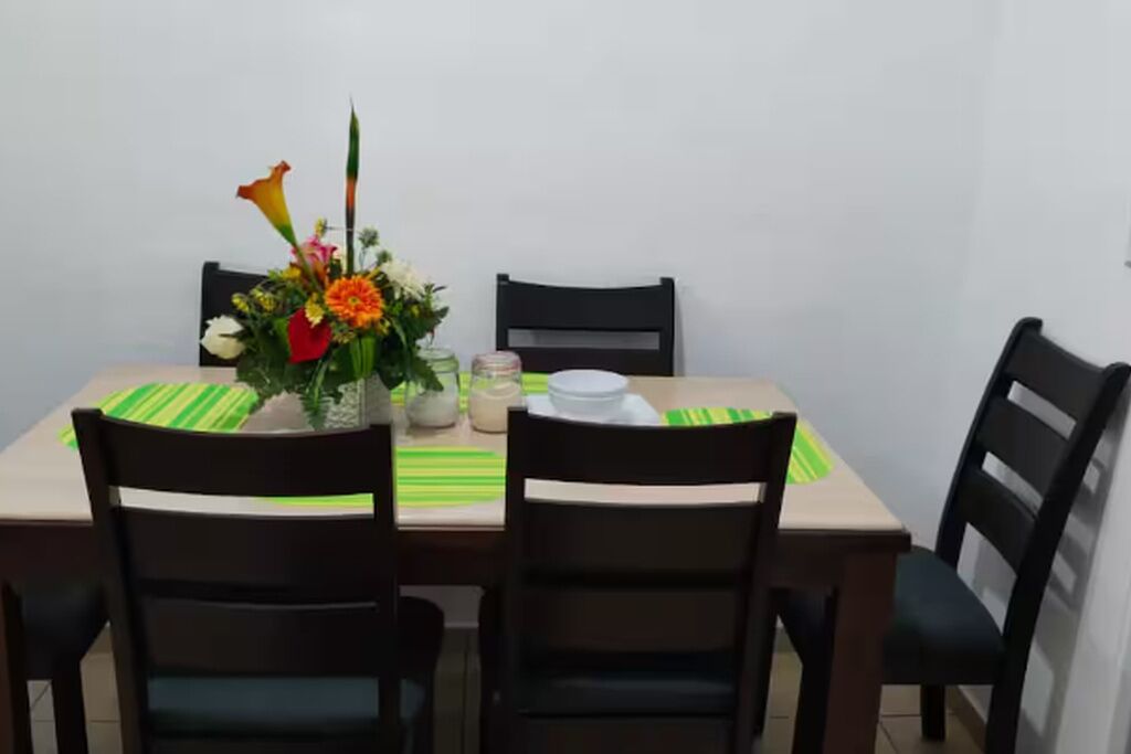 Una taula de menjador amb caires, un centre de taula floral i una placemat a ratlles verdes.