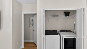A laundry room with a washing machine, dryer, and a shelf with a bucket. - Relax in Englewood 3BR 2BA Home Close to Beaches (Englewood)
