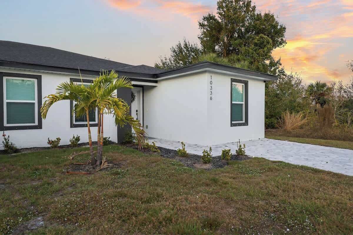 A modern two-story house with a white exterior, numbered 10336, featuring a front porch and a small palm tree.