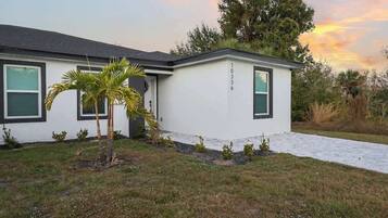 A modern two-story house with a white exterior, numbered 10336, featuring a front porch and a small palm tree.