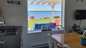 A kitchen with a window, a dining table, and a TV. - Tiny Beach House (Cocagne)