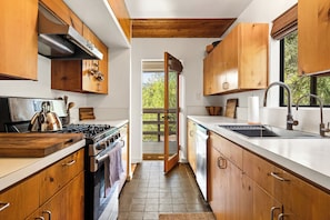 A modern kitchen with wooden cabinets, a stainless steel stove, and a large window. - Spacious 3BR/ 2BA Topanga Home – Nature Retreat w AC and Laundry (Topanga)