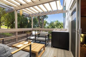 A covered outdoor area with a wooden table, two chairs, a sofa, and a cabinet. - Spacious 3BR/ 2BA Topanga Home – Nature Retreat w AC and Laundry (Topanga)